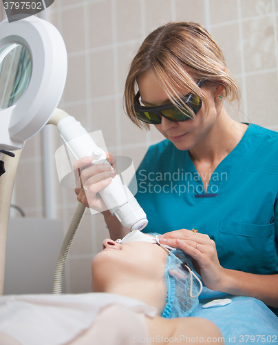 Image of Cosmetician providing facial treatment with a laser