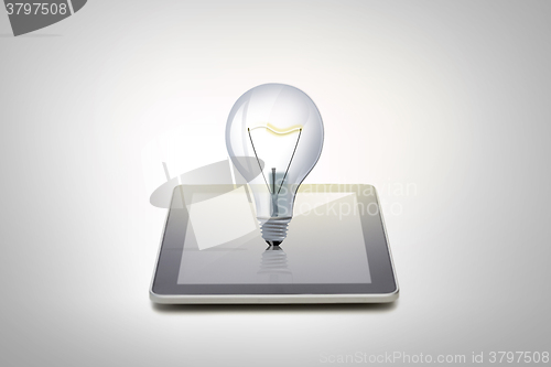 Image of close up of tablet pc computer with light bulb