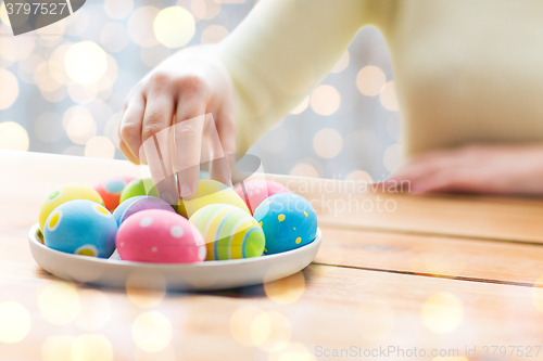 Image of close up of woman hands with colored easter eggs
