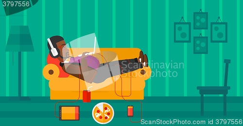 Image of Man lying on sofa with many gadgets.