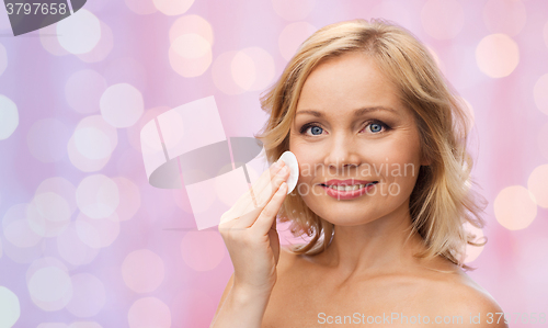 Image of happy woman cleaning face with cotton pad