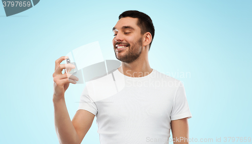 Image of smiling man with male perfume over gray background