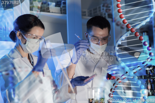 Image of scientists with pipettes and test tubes in lab