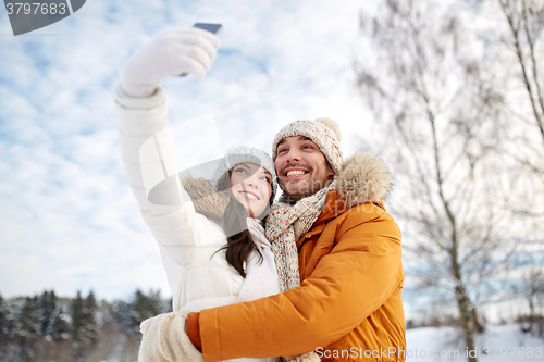 Image of happy couple taking selfie by smartphone in winter