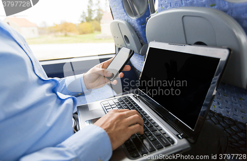 Image of man with smartphone and laptop in travel bus