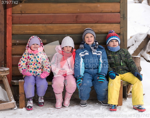 Image of little children group sitting  together  in front of wooden cabi