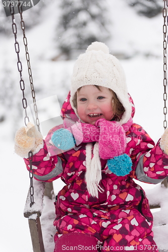 Image of little girl at snowy winter day swing in park