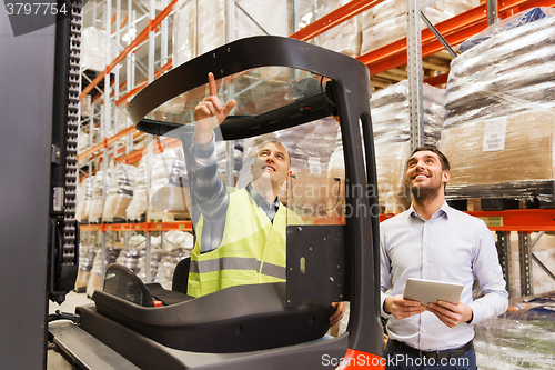 Image of men with tablet pc and forklift at warehouse