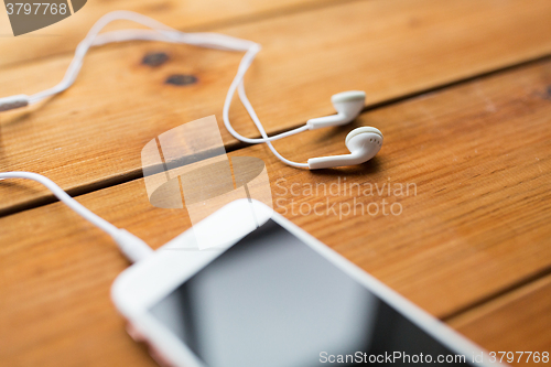 Image of close up of smartphone and earphones on wood