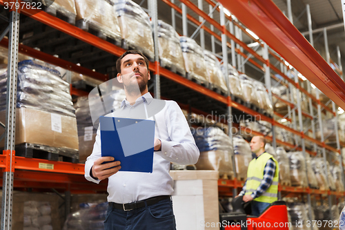 Image of businessman with clipboard at warehouse