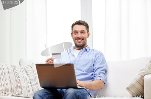 Image of smiling man with laptop and credit card at home