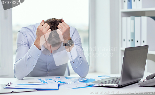 Image of stressed businessman with papers in office