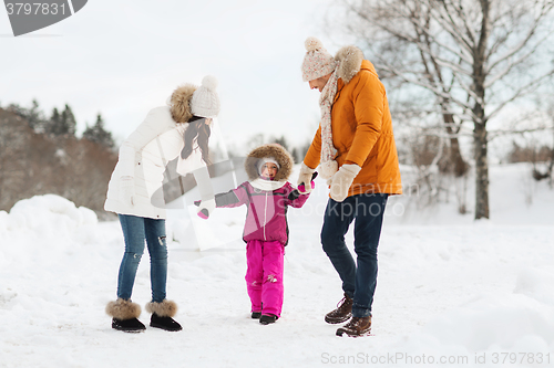 Image of happy family in winter clothes walking outdoors