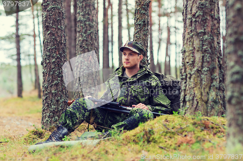 Image of young soldier or hunter with gun in forest