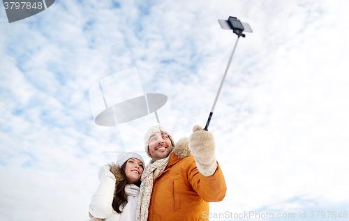 Image of happy couple taking selfie by smartphone in winter