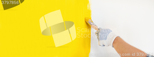 Image of close up of male in gloves painting a wall