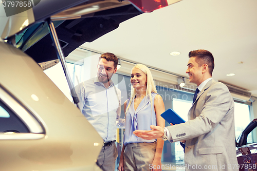 Image of happy couple with car dealer in auto show or salon