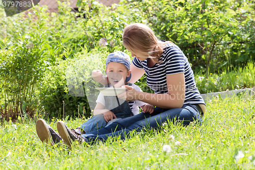 Image of Mother feeding her son on the grass