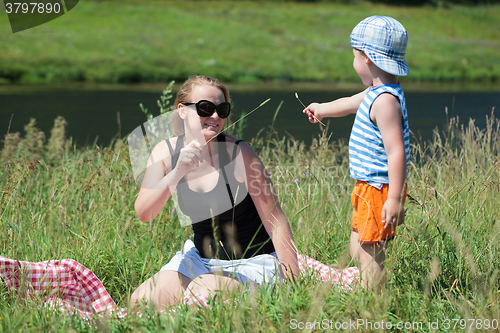 Image of Mother and son playing with grass on the meadow