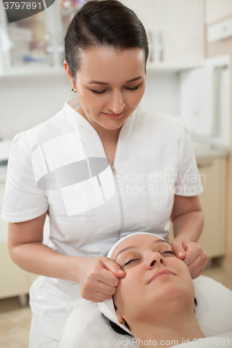 Image of Woman under facial massage at beauty spa