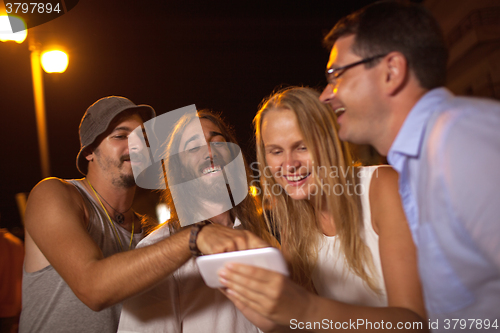 Image of Young friends laughing at what they see on mobile