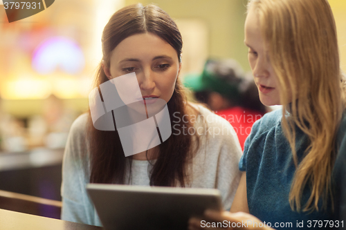 Image of Two women have a discussion in the restaurant using electronic tablet