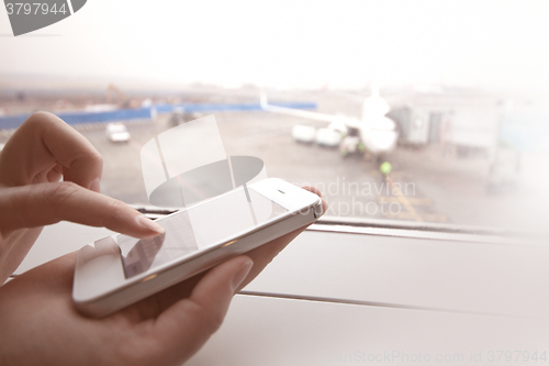 Image of Woman using smart phone by the window at aiport