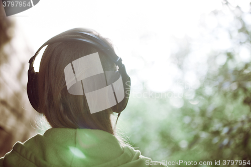 Image of Woman in headphones against bright sunlight