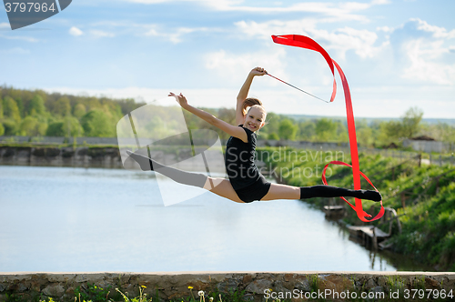 Image of Gymnast girl doing leg-split in a jump with ribbon
