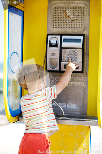 Image of Young boy talking to the phone in a booth