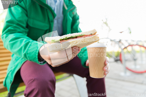 Image of close up of man with coffee and sandwich on street