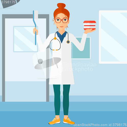 Image of Dentist with dental jaw model and toothbrush.