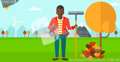 Image of Man with rake near tree and heap of leaves.