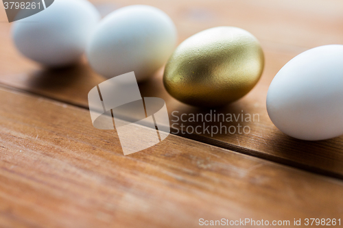 Image of close up of golden and white easter eggs on wood