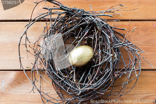 Image of close up of golden easter egg in nest on wood