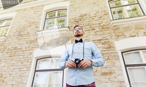 Image of happy young hipster man with film camera in city