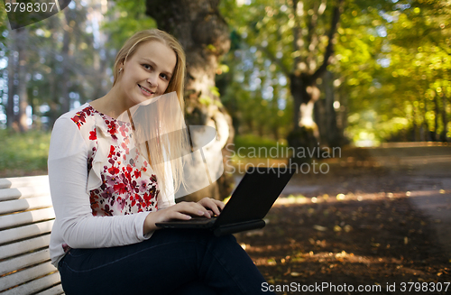 Image of Young woman using her laptop in the park