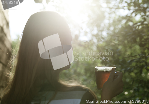 Image of Woman with cup of tea in evening sunlight