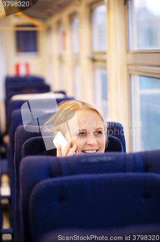 Image of Smiling woman talking on the phone in train.