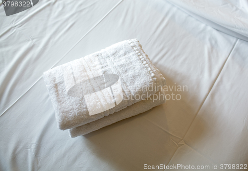 Image of Pile of white clean towels on the bed