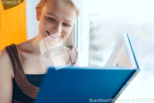 Image of Young smiling woman reading a book