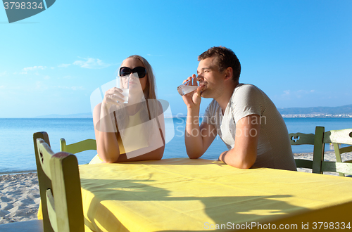 Image of Young couple enjoying drinks at the seaside