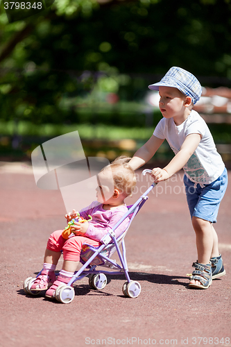 Image of Boy pushing sister in a stroller