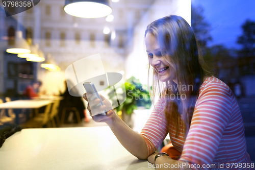 Image of Young woman sitting in a restaurant using mobile