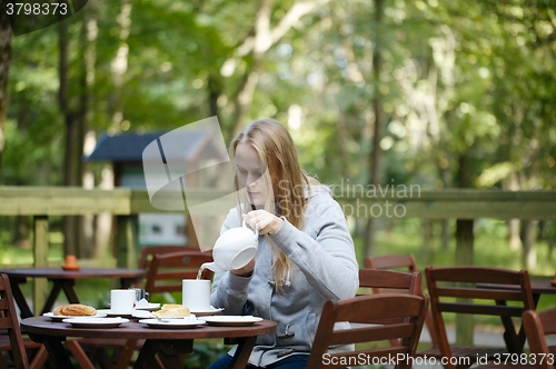Image of Young woman enjoying a pot of tea