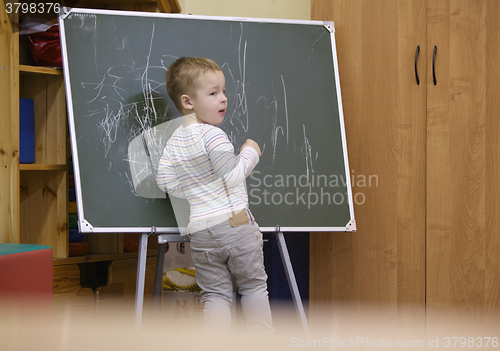 Image of Creative little boy drawing on a chalkboard