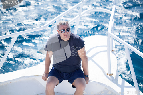 Image of Man sitting on the prow of a boat