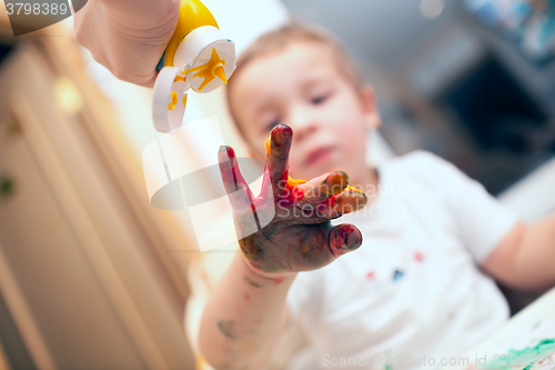 Image of Pressing finger-paint on boys hand