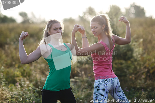 Image of Two athletic girls flexing their arm muscles