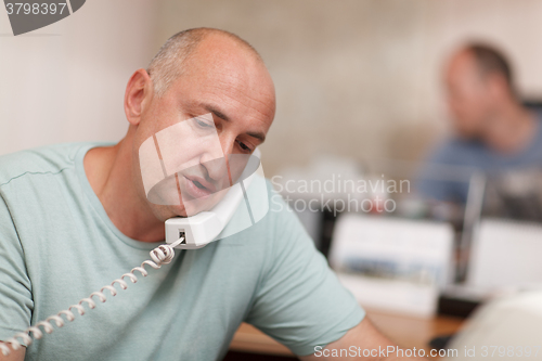 Image of Businessman talking on phone in office